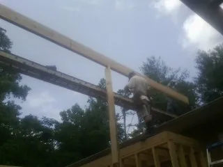 Carpenter setting a ridge beam over a new addition frame — Ice Dam Removal by Roofing Brothers in Grasston