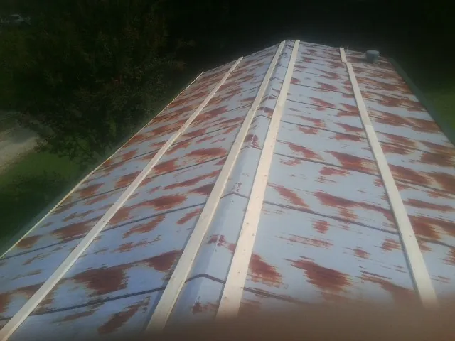 Rusted metal roof panels with new wood purlins before replacement — Storm Damage Roof Repair in Grasston by Roofing Brothers