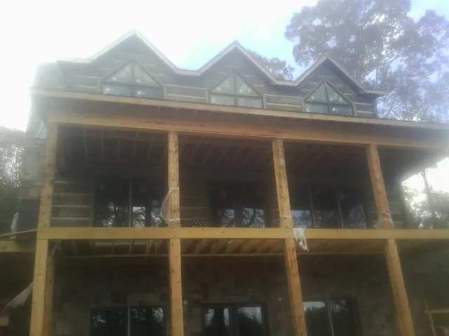 Dormers and porch framing on a large log home under construction — Roof Coating work by our crew in Grasston
