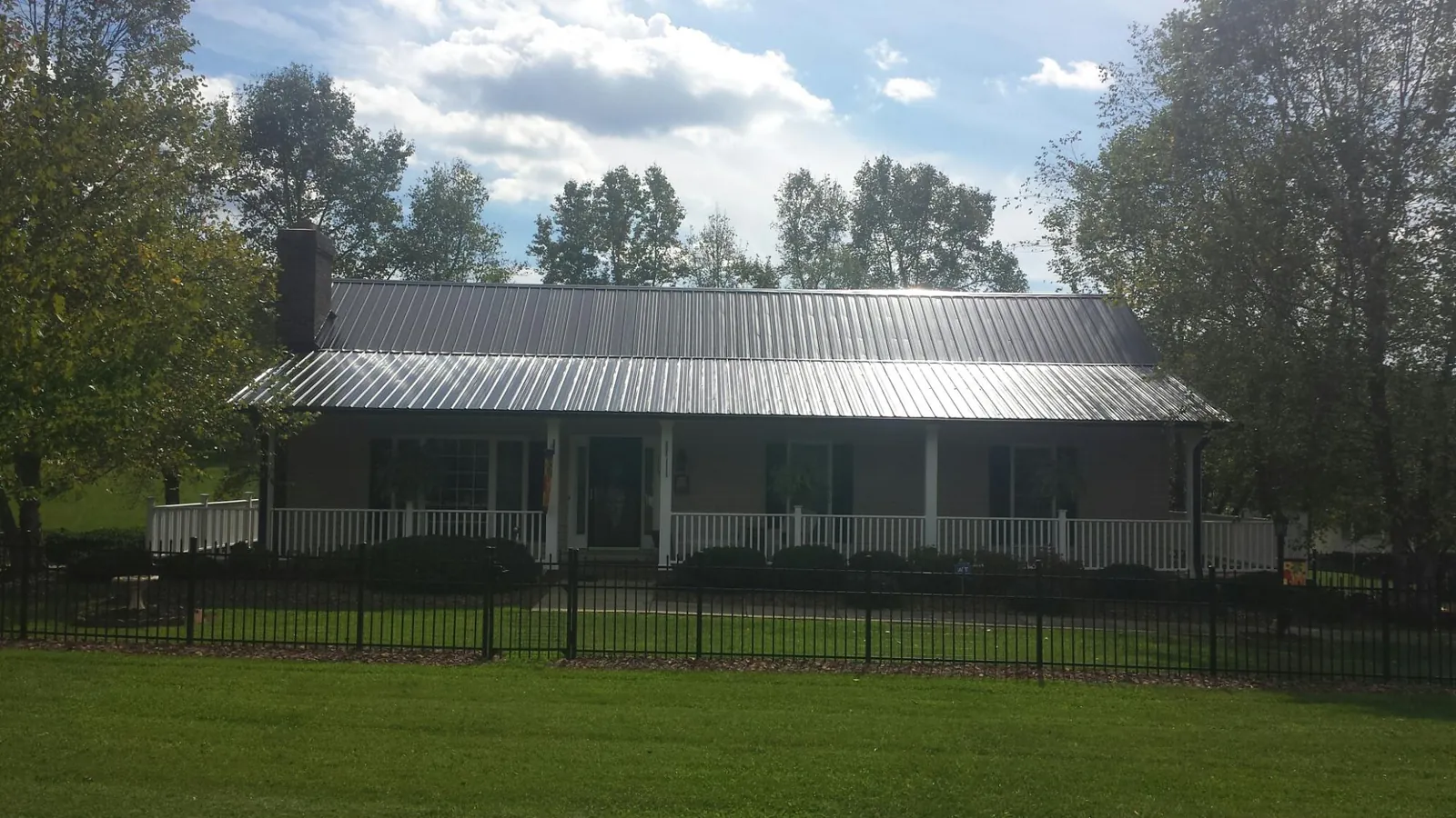Gray metal roof on a brick ranch with a full width front porch — Gutter Guard Installation work by our crew in Grasston