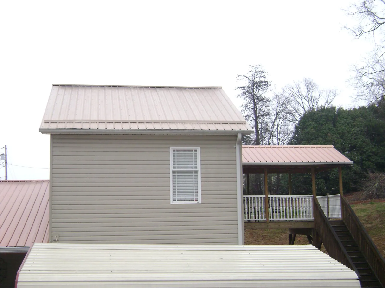 Tan metal roofs on a two story addition and attached porch, from a Roof Replacement job in Grasston