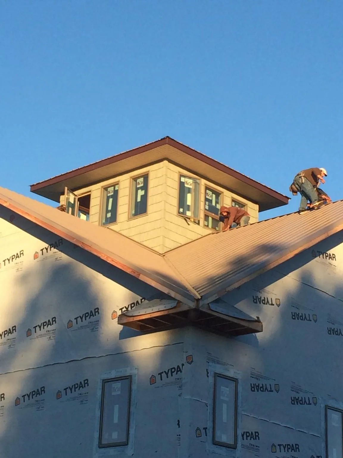 Roofers working around a rooftop cupola on a new metal roof at sunset — Roof Waterproofing in Grasston by Roofing Brothers